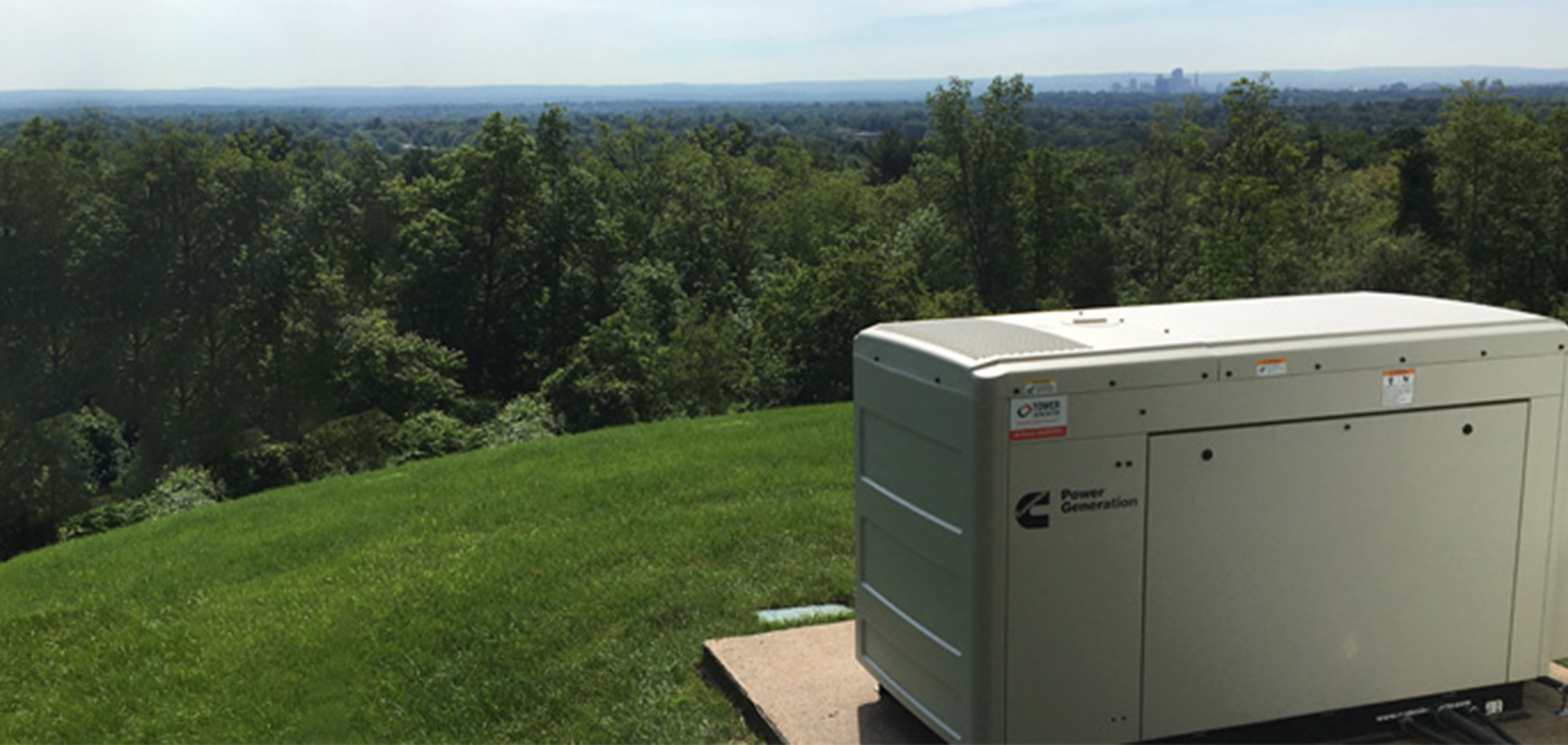 Hillside overlooking a forested area with a generator in the foreground.