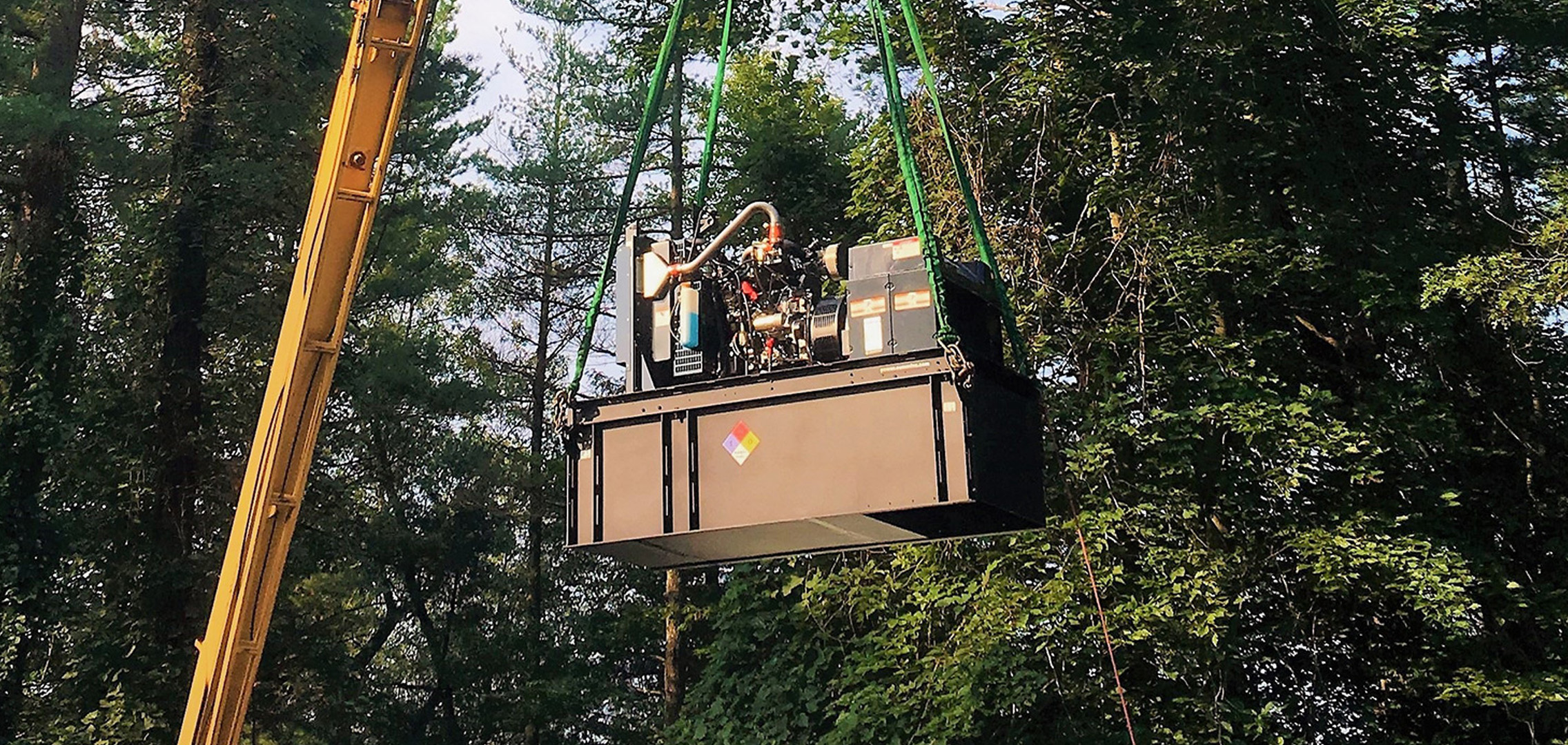 A commercial generator being airlifted by a crane
