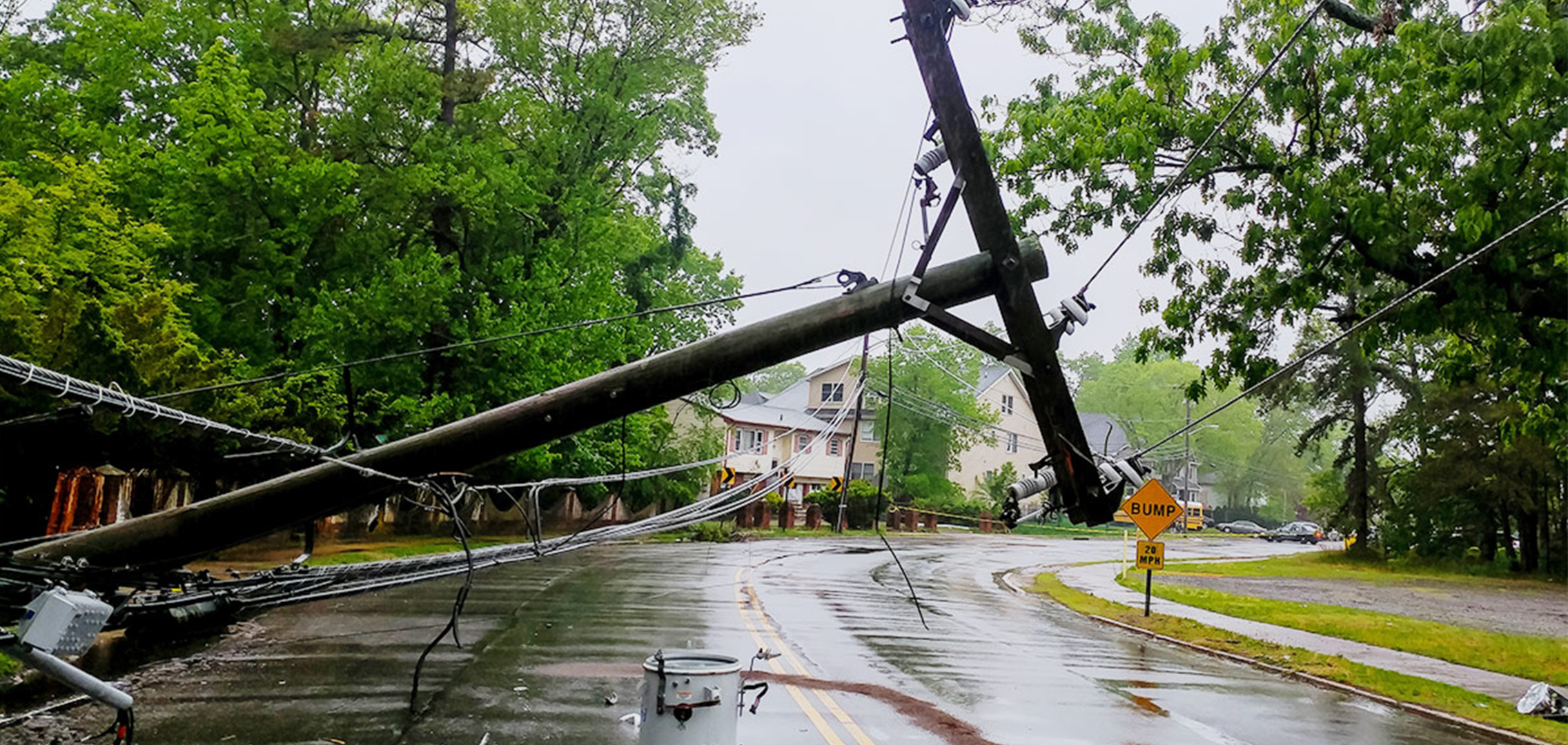 Downed telephone pole over a street in a residential neighborhood.