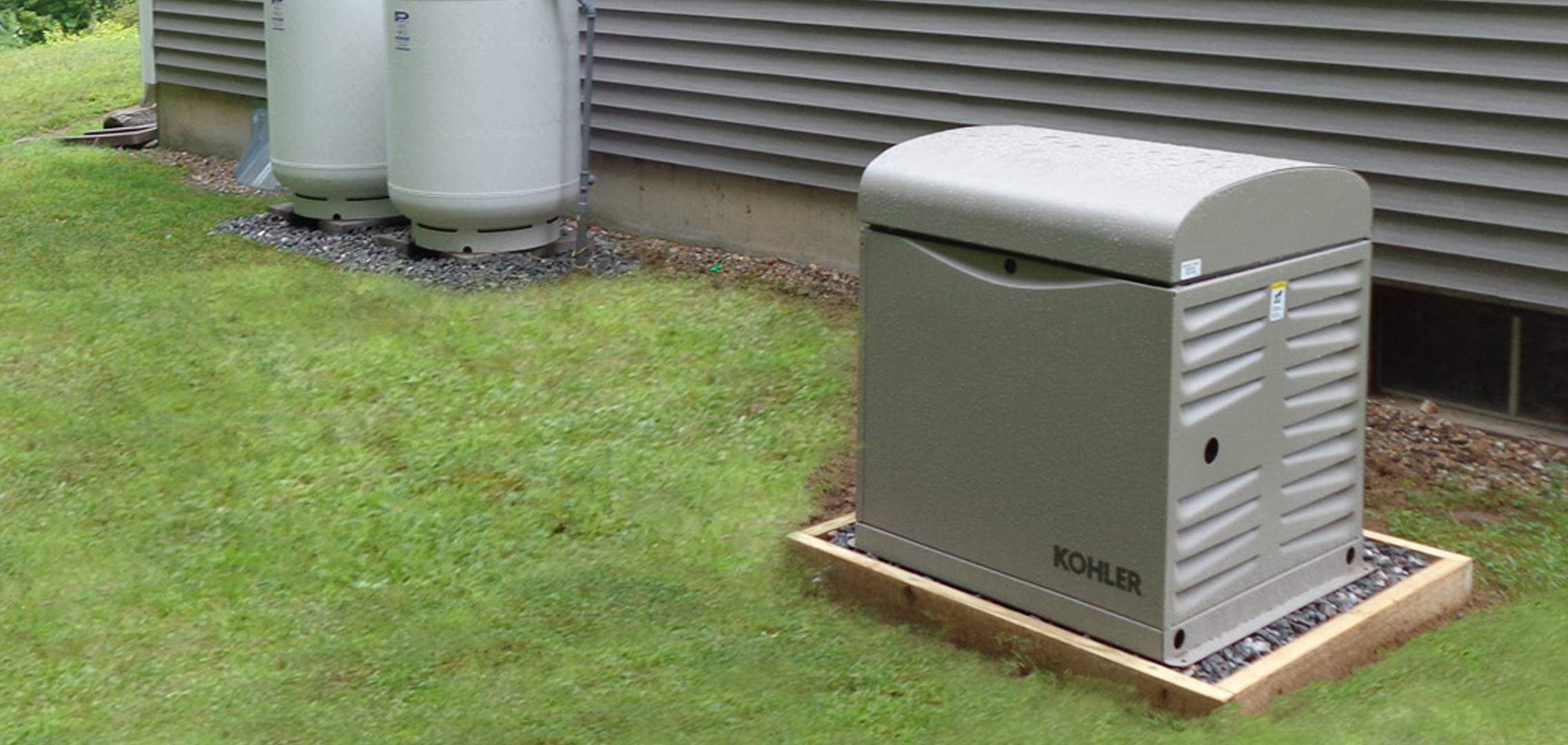 Residential generator next to two propane tanks