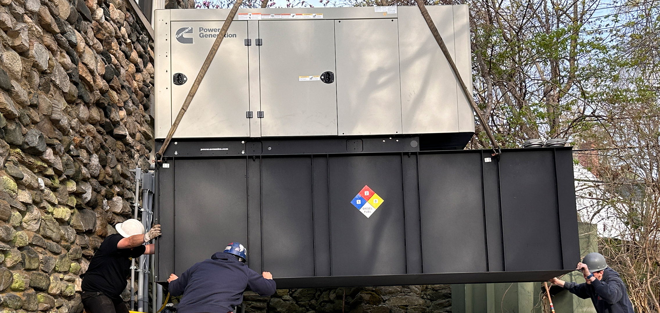 Generator being placed down with Tower employees helping guide the generator