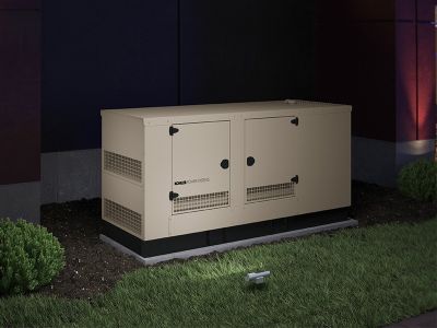 Commercial generator outside of building at night illuminated by lights