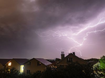 Houses with lights on during a storm with lightning