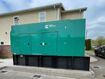 A green commercial generator outside of a building